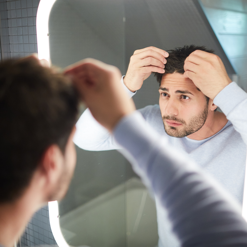 Man looking at his hair loss in mirror